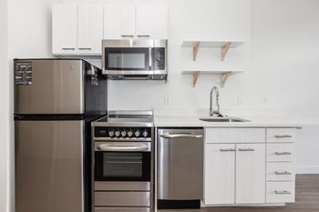 A modern kitchen with a stainless steel refrigerator, oven, and microwave.